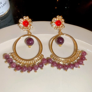 Macro detail of vintage tassel earrings with red gemstones and purple beads in gold