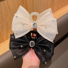 Detail of velvet mesh bow hair clips with rhinestone accents in cream and black