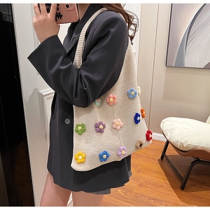 Detailed macro view of 3D colorful crochet floral patterns on a cream knit tote bag