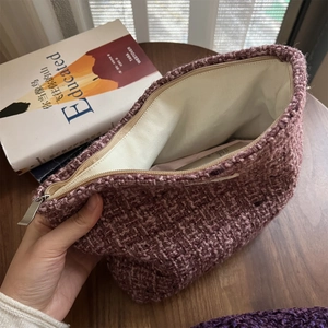 Detail of tweed makeup bag showing the thick woven texture and silver metal zipper closure