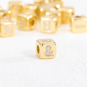 Macro shot of gold-plated cube spacer bead with sparkling cubic zirconia ampersand detail