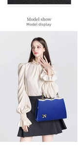 Detail of navy blue leather handbag with a large gold bow and textured finish