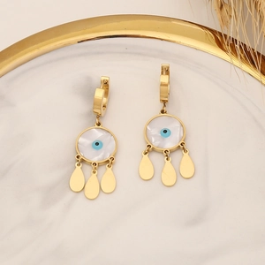 Detail of gold hoop earrings with evil eye motif and three teardrop charms on marble