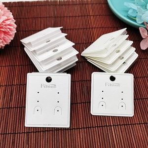 Close-up of white PVC earring display cards with Fashion and S925 labels on bamboo background