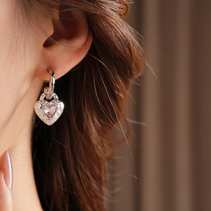 Detail of silver heart drop earring with pink gemstone on model for an elegant look