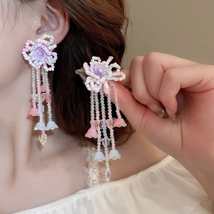 Detail of sweet floral tassel earrings with colorful resin beads worn by a female model