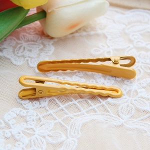 Detail of yellow wave-textured metal hair clips on romantic lace with tulip decoration