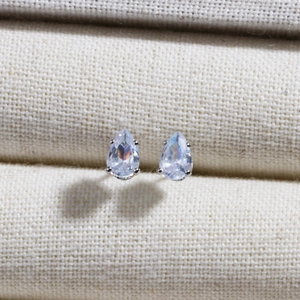 Macro detail of tear-drop cubic zirconia earrings with silver claw setting on fabric