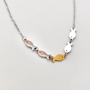 Detailed view of five small fish charms in silver, gold, and rose gold finishes