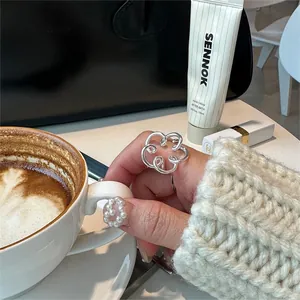 Detailed view of an openwork floral sterling silver ring on a model holding a coffee cup