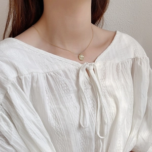 Close-up of a vintage golden coin pendant with embossed texture on a fine link chain