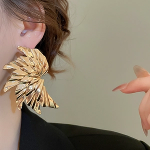 Macro shot of large gold pleated metal earrings with unique fan-shaped wing texture