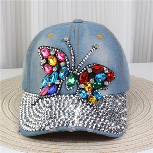 Macro view of blue denim baseball cap featuring colorful gemstone butterfly and rhinestones