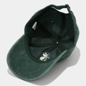 Detail of green washed cotton cap interior showing 100% cotton label and reinforced seams