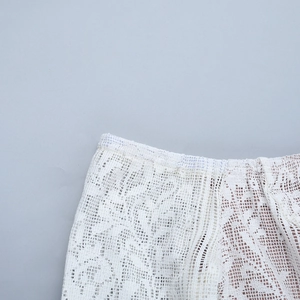 Gros plan sur la dentelle blanche avec motifs floraux et structure en maille fine