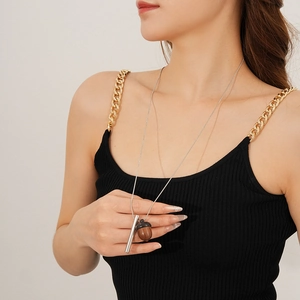 Detail view of wooden acorn pendant and silver metal cylinder on a slim necklace chain