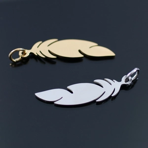 Macro shot of 18K gold and silver feather pendants with rings on a black mirror surface