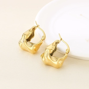 Detailed view of polished 18K gold irregular geometric earrings on a textured background