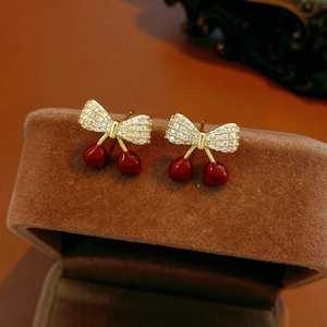 Vue macro des boucles d'oreilles cerise avec émail rouge et zircon sur boîte en velours