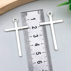 Vista dettagliata di due ciondoli a croce argento di 48mm x 28mm con righello per scala