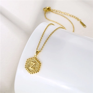 Close-up of golden hexagonal pendant featuring letter Z with textured finish on a chain