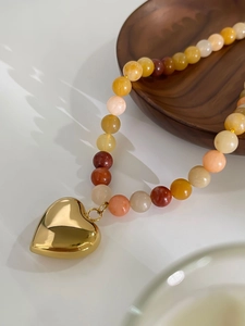 Detailed macro of a polished golden heart pendant with colorful mixed natural stone beads