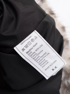 Nahaufnahme des Pflegeetiketts mit 100 % Polyester auf der Kunstpelzjacke