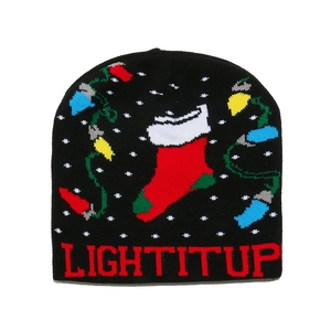 Close-up of black knit Christmas beanie featuring Light It Up text and festive patterns