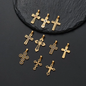 Zehn goldene Edelstahl-Kreuzanhänger in verschiedenen Designs auf dunklem Stein