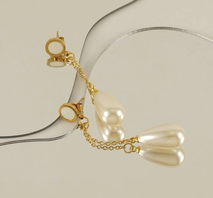 Detail of 18K gold stainless steel long drop earrings with elegant white pearl beads