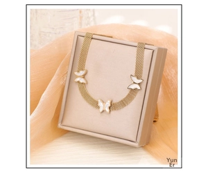 Detail of a gold butterfly mesh chain necklace with white mother-of-pearl style inlays