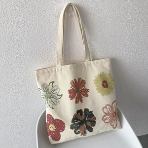 Close-up of canvas tote bag featuring minimalist hand-painted floral patterns on a chair
