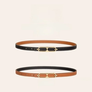 Detail of reversible thin leather belt in black and brown with a golden hollow metal buckle