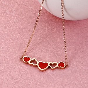 Close-up of a gold chain bracelet with red enamel and hollow heart-shaped charms