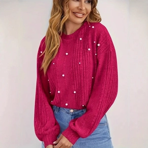 Détail du pull en tricot rose fuchsia avec manches lanterne et ornements de perles