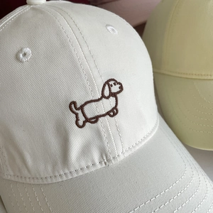 Close-up of cute cartoon brown dachshund embroidery on white cotton baseball cap