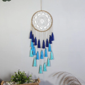 Bohemian dream catcher with white crochet center and blue gradient tassels hanging on wall