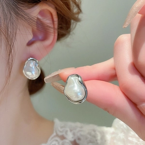 Macro detail of baroque imitation pearl earrings with irregular silver metal edges