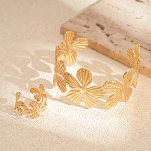 Detailed view of golden flower ring and open cuff bracelet with metallic texture