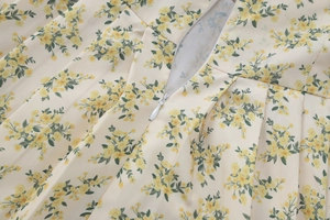 Détail d'une robe fleurie sur fond beige avec une fermeture éclair invisible et fluide