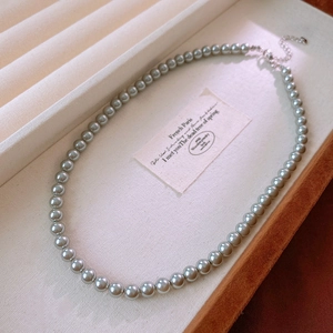 Detailed macro view of silver-grey pearl necklace on linen display tray with silver clasp