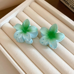 Detailed macro view of two blue gradient flower hair claws on a beige velvet jewelry tray