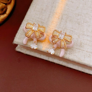 Detailed macro view of pink enamel bow earrings with sparkling white cubic zirconia