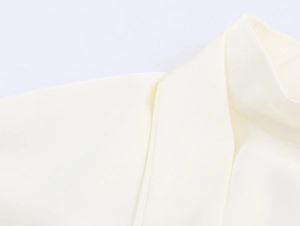 Detailopname van de elegante halslijn en schouder van de crèmekleurige satijnen jurk