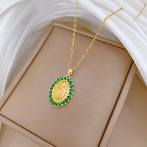 Detail of gold oval portrait pendant with green crystals on beige jewelry box