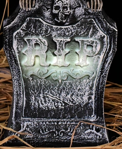 Close-up of glowing RIP gravestone decoration with skull detail and gray stone texture