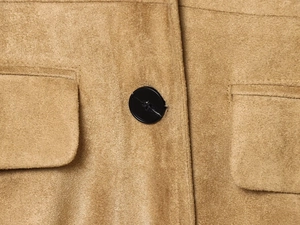 Close-up of brown suede fabric texture with black round buttons and utility pockets