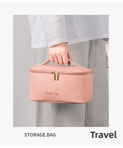 Pink crosshatch leather cosmetic bag with gold zippers held by a hand for travel