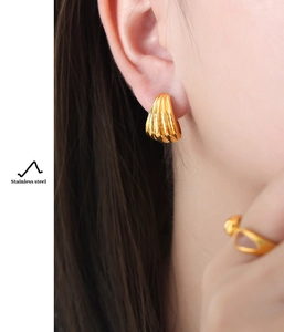 Detail of 18K gold plated stainless steel U-shaped earrings with shell texture on model