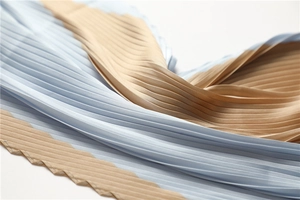 Close-up of pleated silk fabric in light blue and champagne with glossy finish